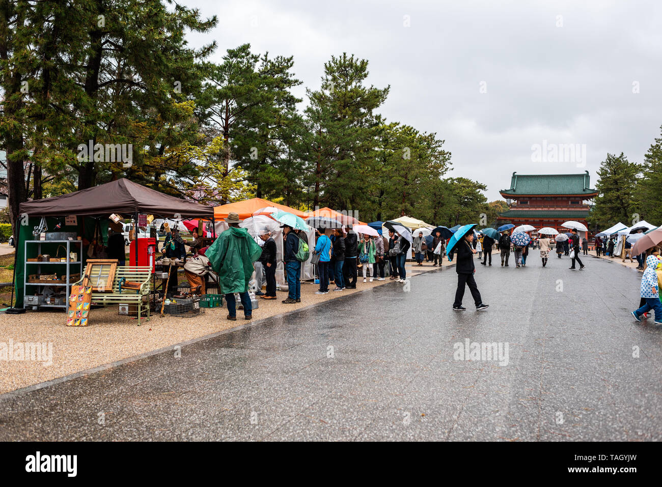 Kyoto, Japan - 10 April, 2019: Menschen mit Sonnenschirmen während der regnerischen Tag zu Fuß im Markt in Okazaki Park mit Blick auf den Heian-schrein Stockfoto