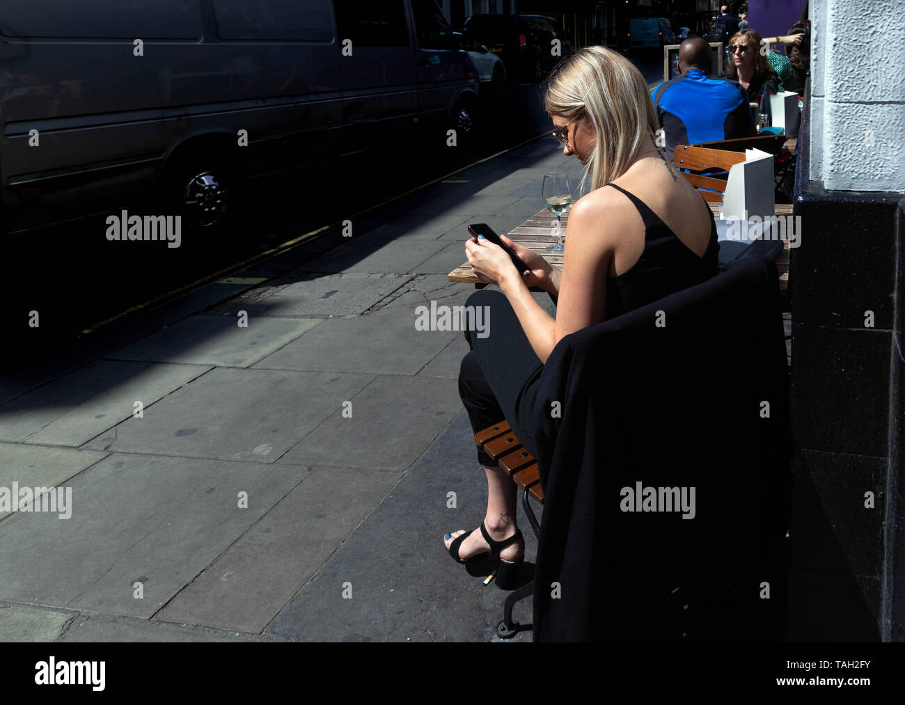 Rückansicht eines weiblichen Benutzer von Mobiltelefonen, Soho, London, England, UK. Stockfoto