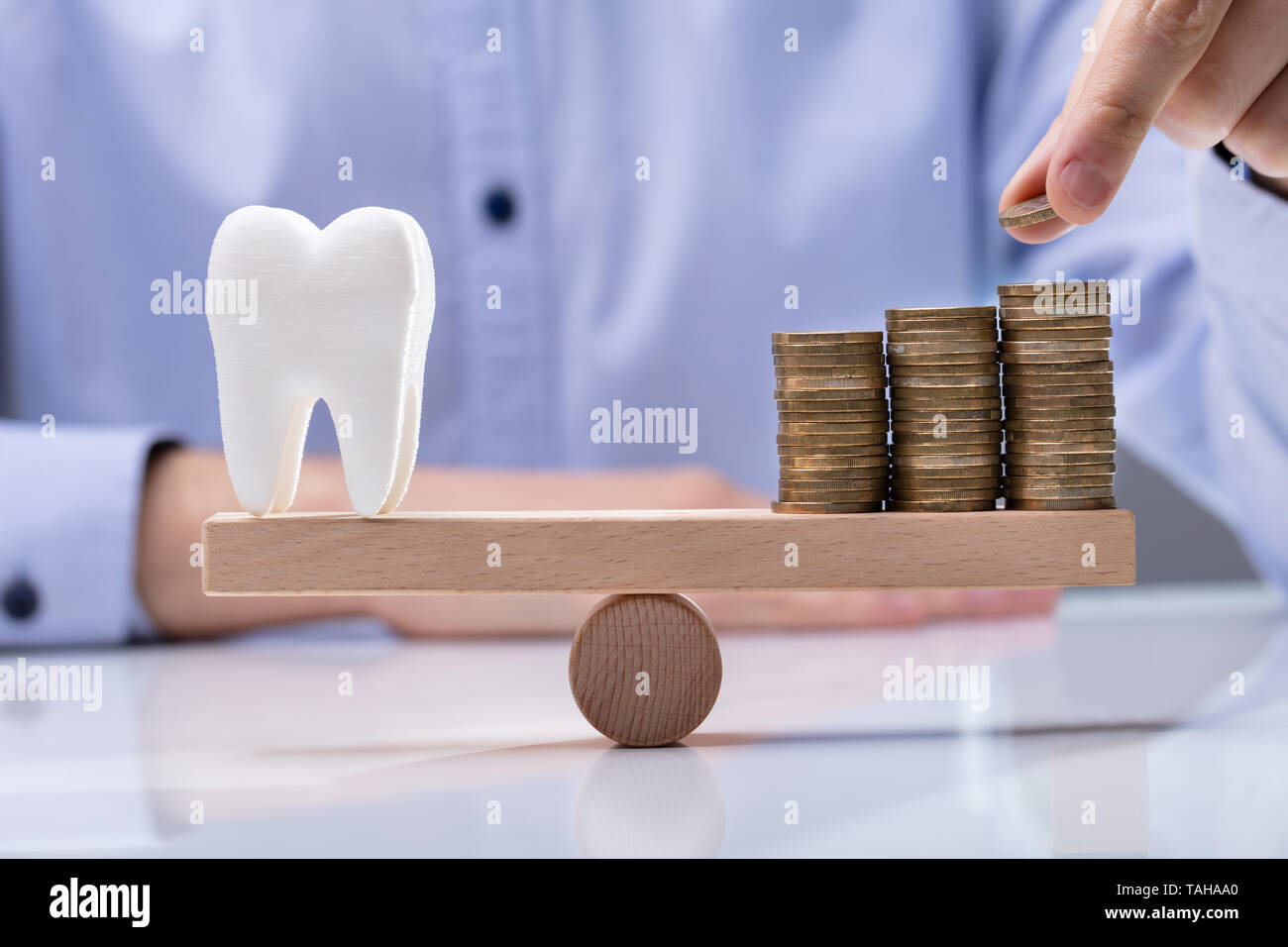 Mann die Münze auf dem Stapel Münzen und Zahn über Wippe Stockfoto