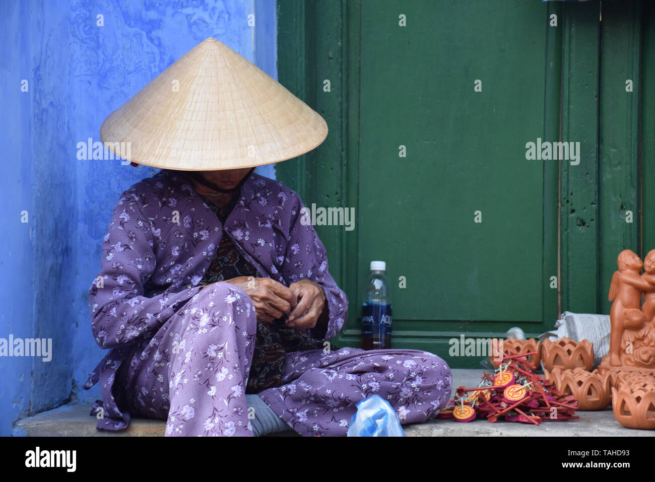 Vietnamesische alte Frau mit konischen hat den Verkauf ihrer Souvenirs auf den Straßen der Altstadt von Hoi An, Vietnam Stockfoto