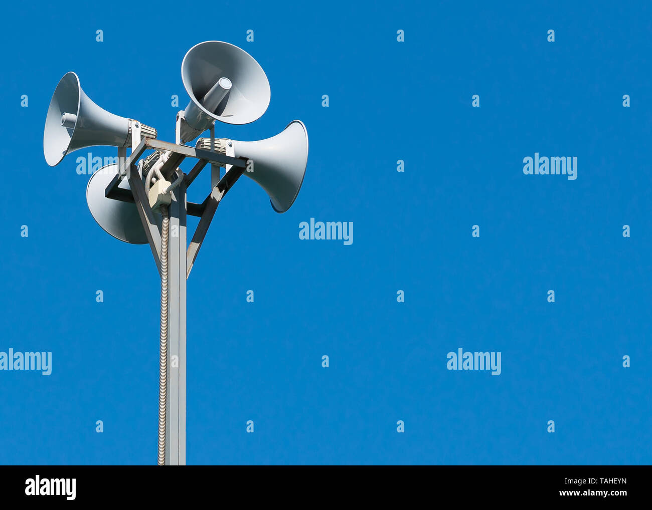 Eine große Säule mit vier grauen Lautsprecher in einem Kreis gegen einen sauberen blauen Himmel. Warnblinkanlage. Die Möglichkeit der Platzierung ihrer Test- oder Bild. Stockfoto