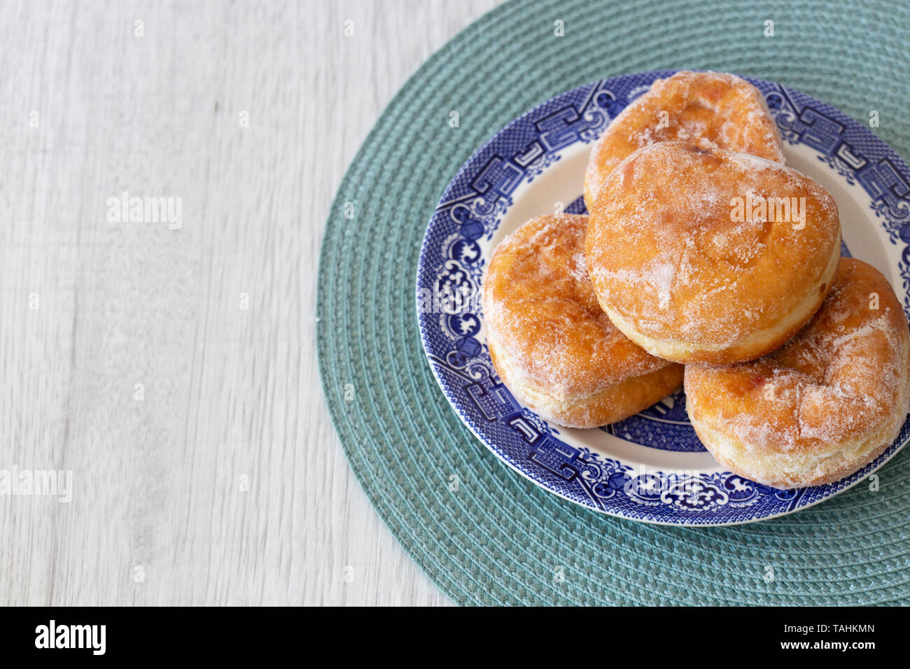Stau Donuts auf einem blauen und weißen Platte und grünen Tisch Matte auf einem grauen Holz Hintergrund Stockfoto