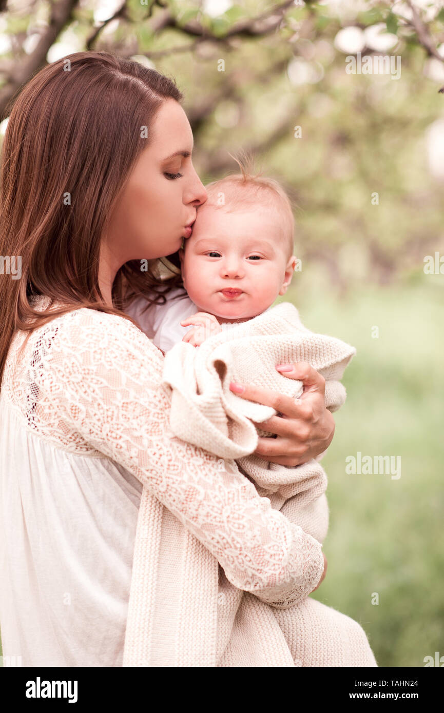 Mutter Holding Baby outdoor über grüne Natur Hintergrund posiert. Stockfoto