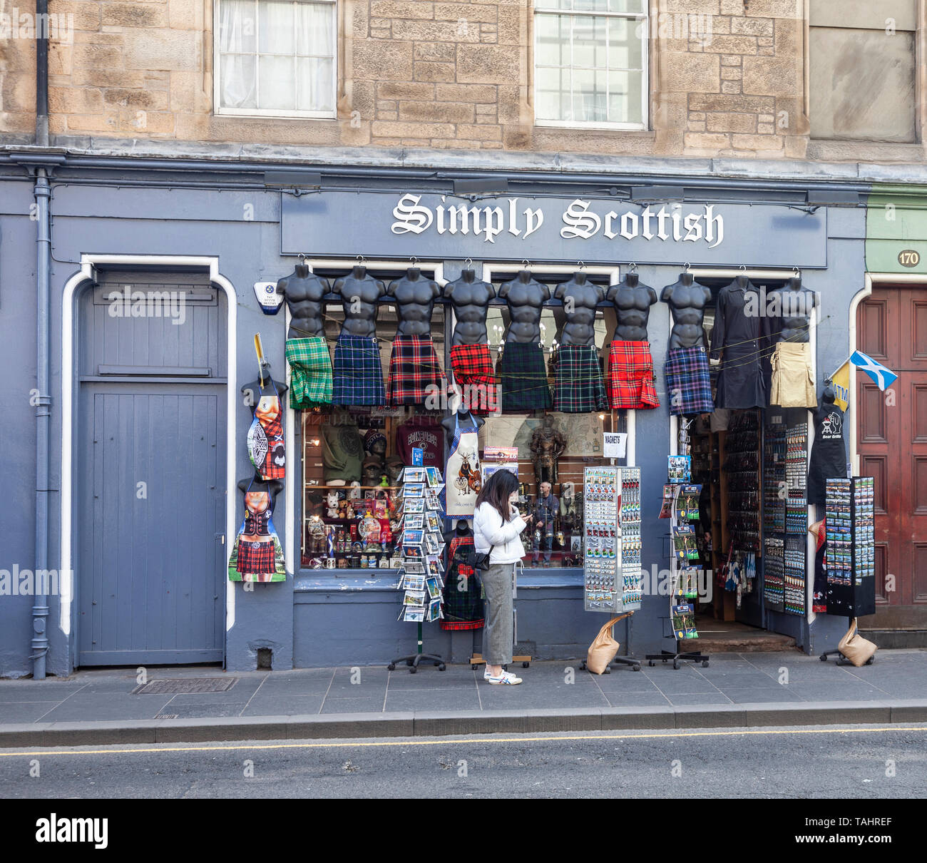 Eine junge Frau, die ihr Telefon Kontrolle außerhalb Einfach Schottischen, ein Geschäft mit schottischen Souvenirs, die in der Royal Mile/Hohe Straße in der Altstadt von Edinbu Stockfoto