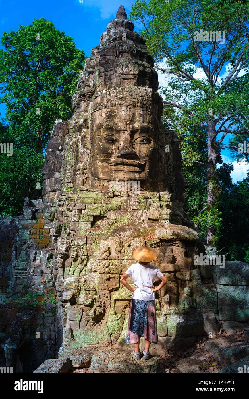 Frau in Bayon Tempel mit Blick auf Stein Gesichter, Angkor Thom, morgen Licht strahlend blauer Himmel. Buddhismus meditation Konzept, weltberühmten Reiseziel, Stockfoto