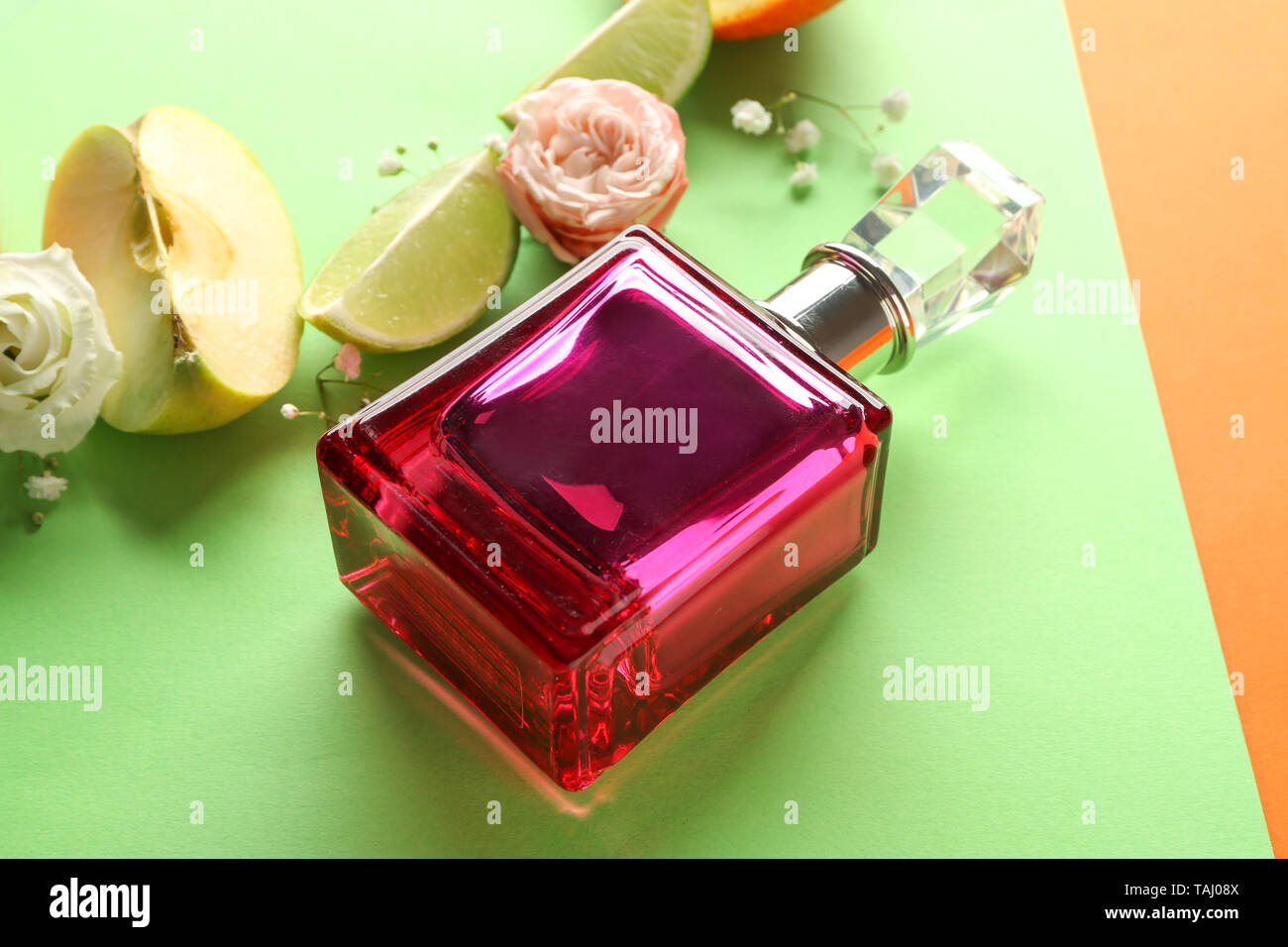 Flasche Parfüm, Früchte und Blumen auf farbigen Hintergrund Stockfoto