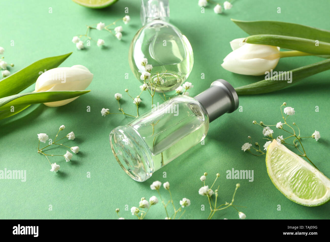 Flaschen Parfüm, Zitrusfrüchten und Blumen auf farbigen Hintergrund Stockfoto