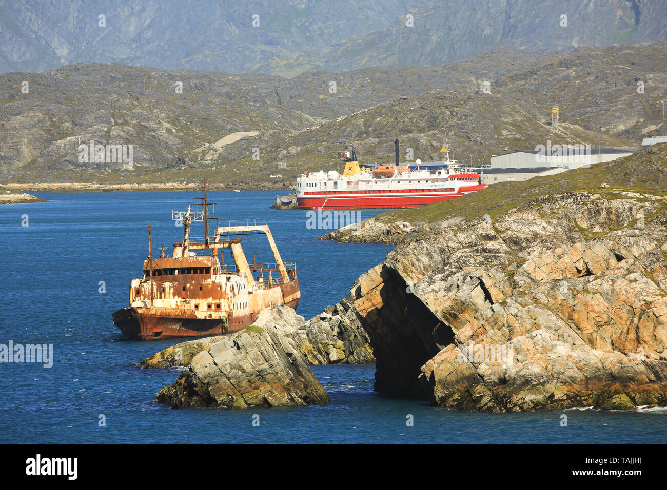 Ein verfallenes Fischerboot am Eingang Paamiut Dorf an der Westküste Grönlands. Der Sarfaq Ittuk Fähre ist im Dorf angedockt. Stockfoto