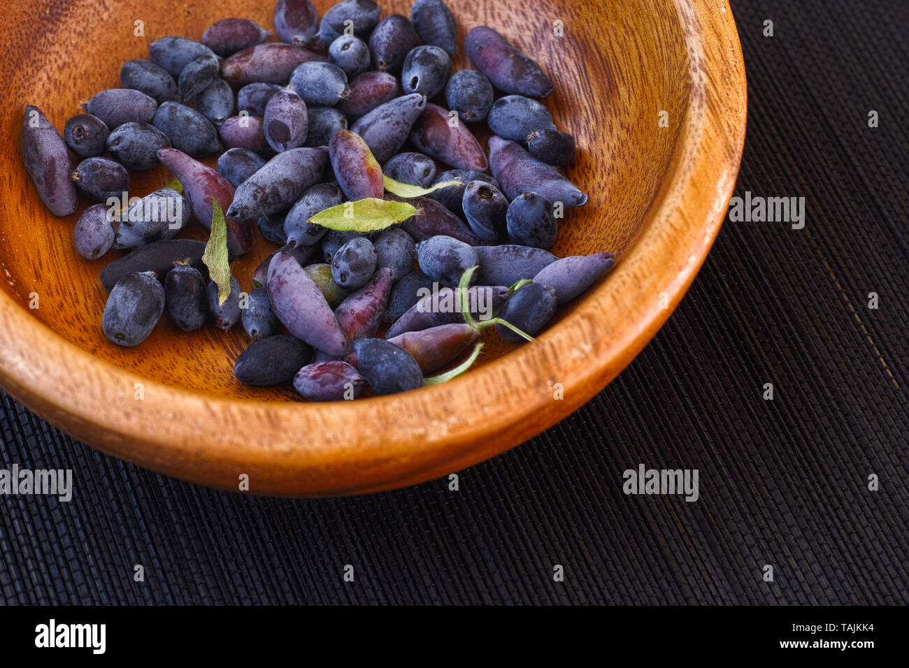 Blue fliegen Geißblatt Beeren in eine hölzerne Schüssel. Close Up. Stockfoto