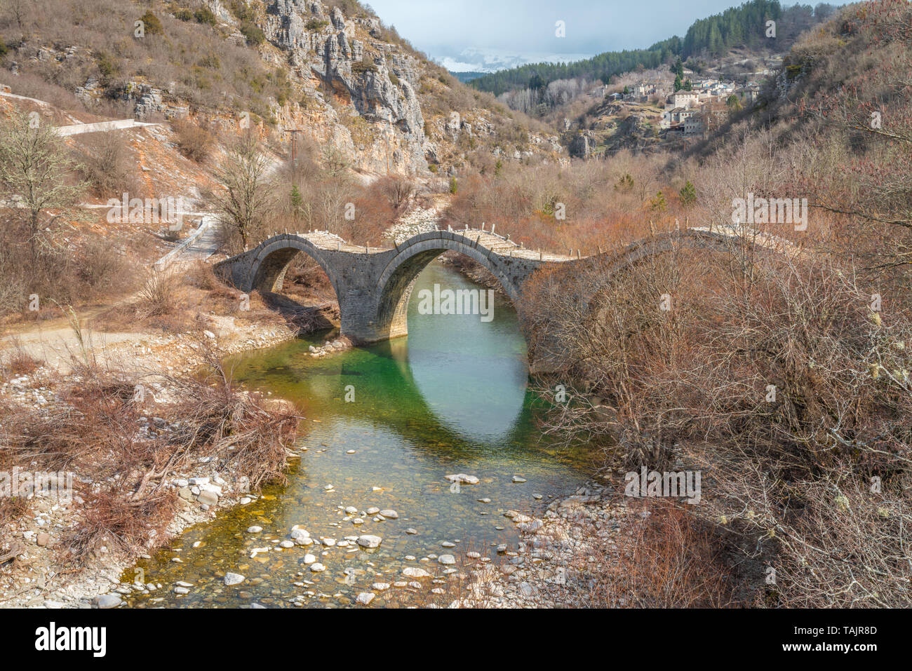 Triple arch Steinbrücke von kalogeriko in Zagoria, Griechenland. Alte steinerne Brücke mit drei Bögen, die einen Fluß überquert, mit smaragdgrünem Wasser in Griechenland Berge. Stockfoto