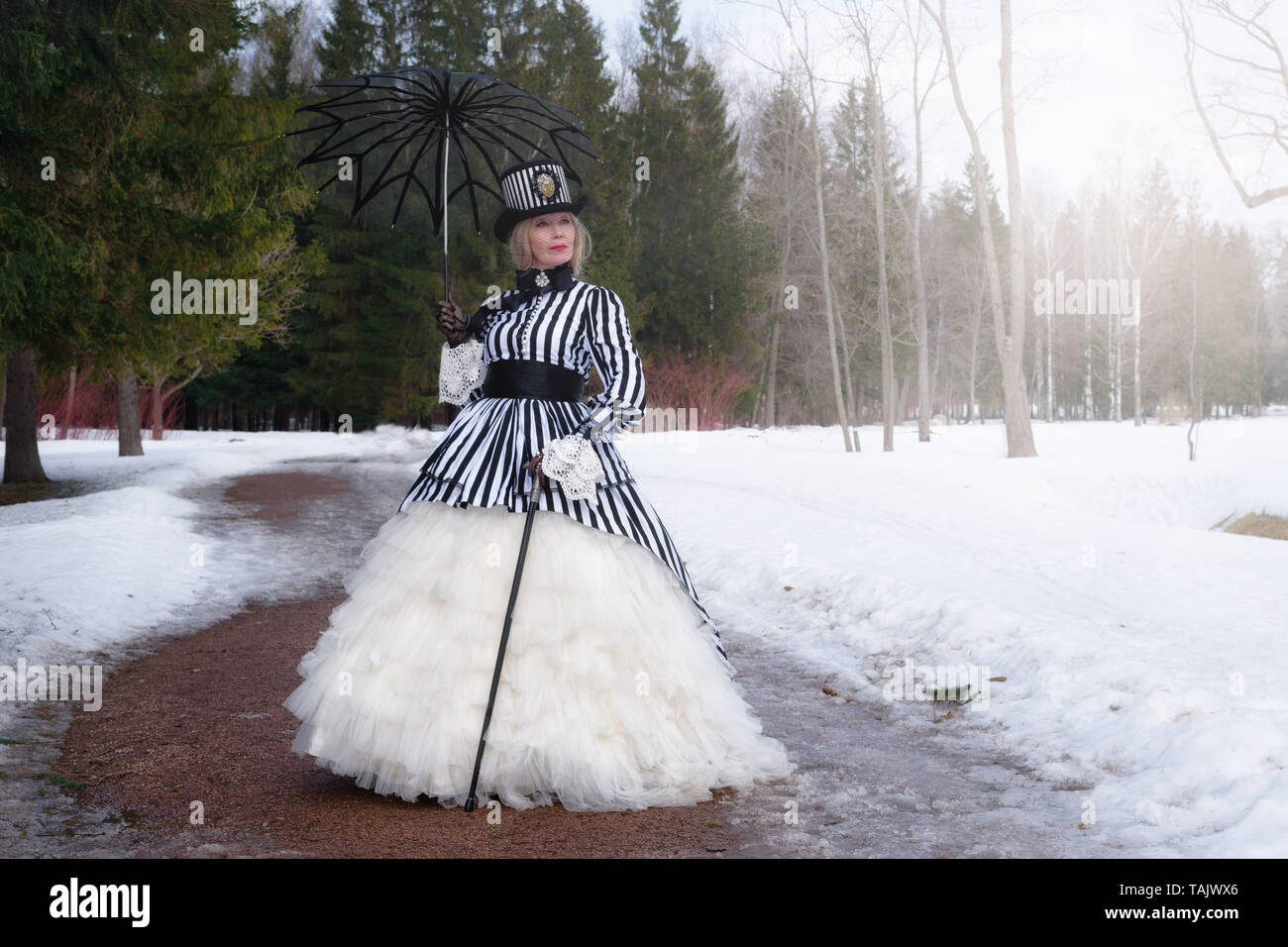 Ältere Frau in einem gothic Kleid in einem Hut mit einem schwarzen Dach auf  die Natur im Winter Stockfotografie - Alamy