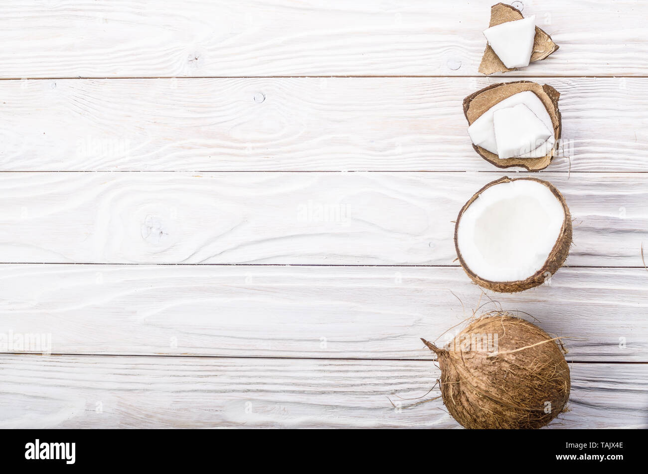 Flach Hintergrund der Kokosnuss, Kokosnussschalen und Fleischstücke auf weissem Holztisch Stockfoto