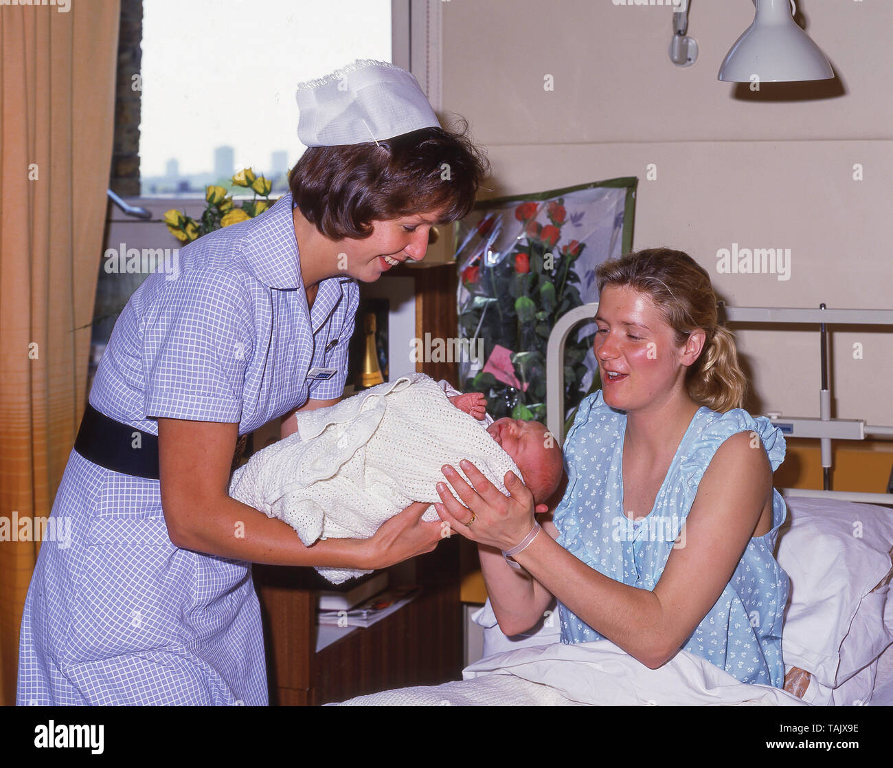 Hebamme Übergabe baby junge Mutter in der Entbindungsstation in privaten Krankenhaus, Greater London, England, Vereinigtes Königreich Stockfoto