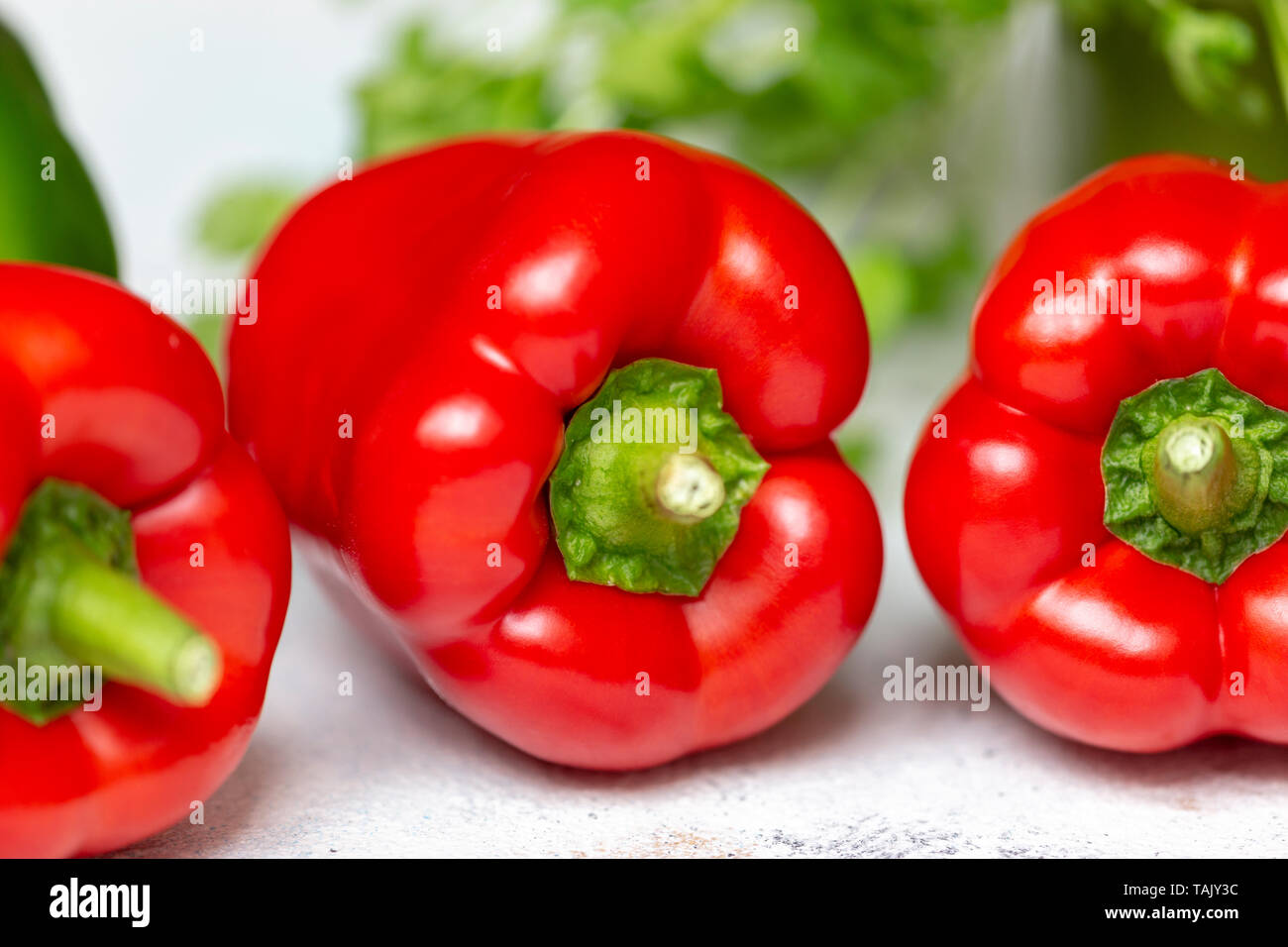 Drei rote Paprika mit Koriander im Hintergrund Stockfoto