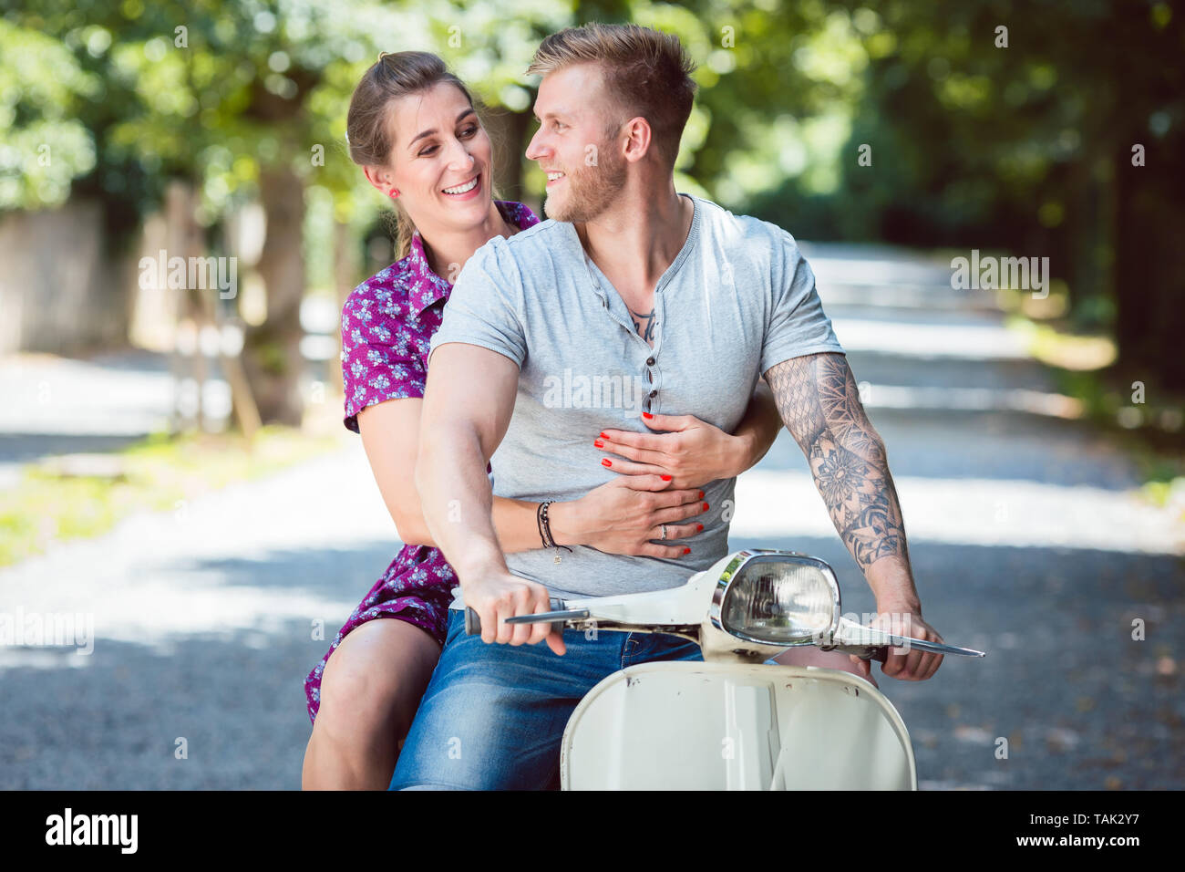 Glücklich lächelnde junge Paar reisen auf altmodische Scooter Stockfoto
