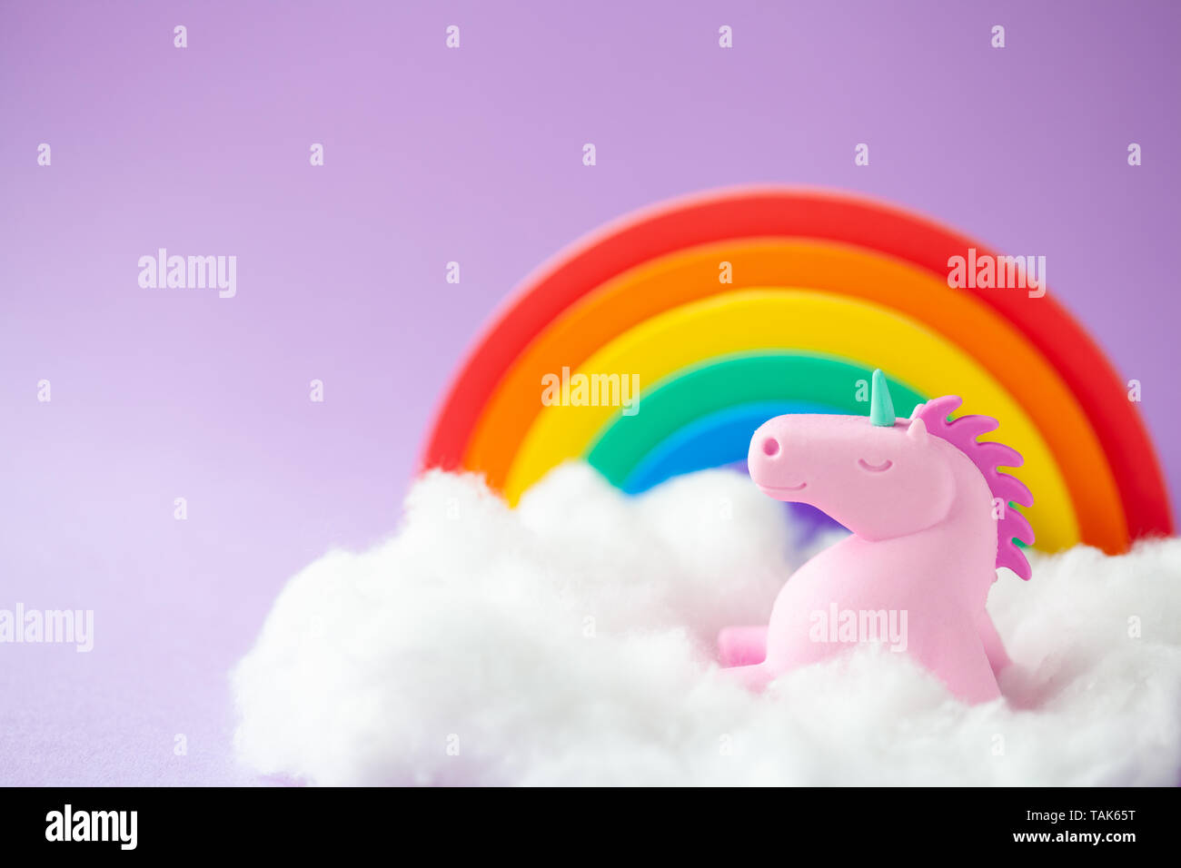 Happy Einhorn sitzt auf einer Wolke mit einem Regenbogen Stockfoto