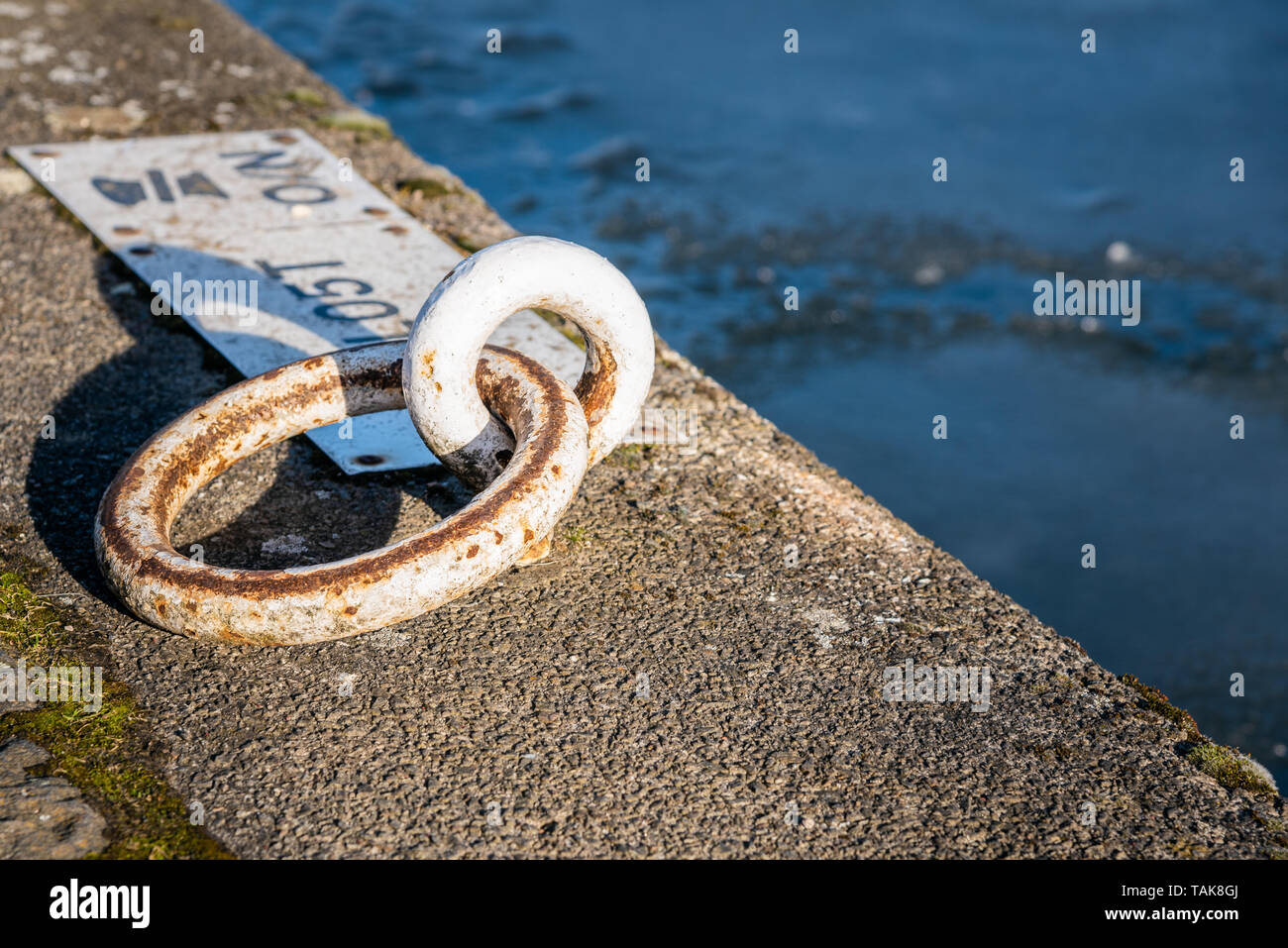 Nahaufnahme eines teilweise rostiges Metall Liegeplatz Ring auf einem Kai entlang eines Kanals Stockfoto