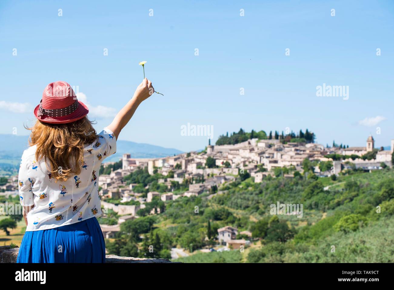 Spello, Perugia, Umbrien, Italien. Panorama der Stadt der Blumen, im grünen Herzen von Italien. Von hinten ein Mädchen in einem Red Hat mit einer Blume. Stockfoto