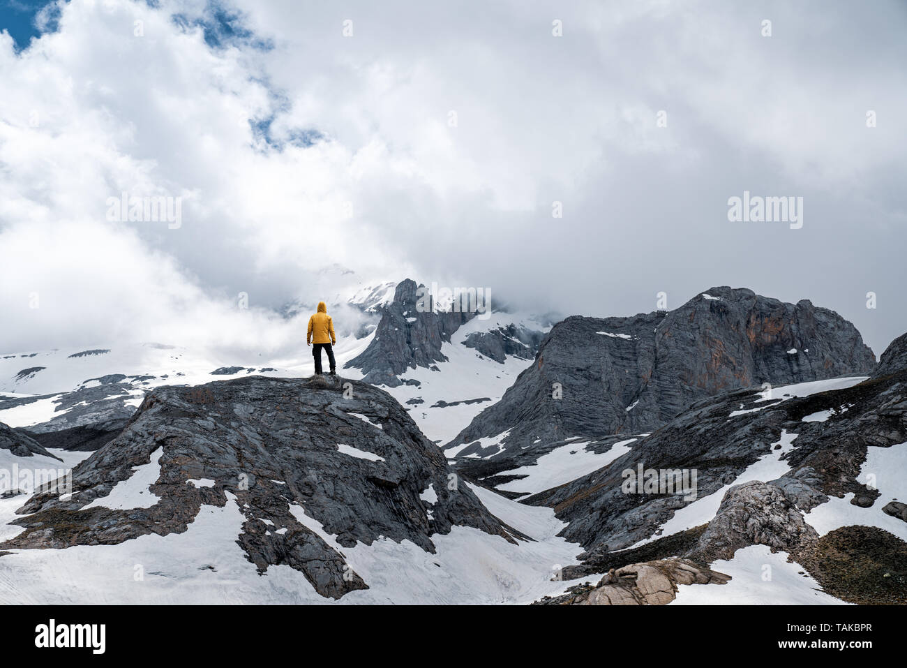 Männliche Wanderer mit gelben Regenmantel auf Berg Stockfoto