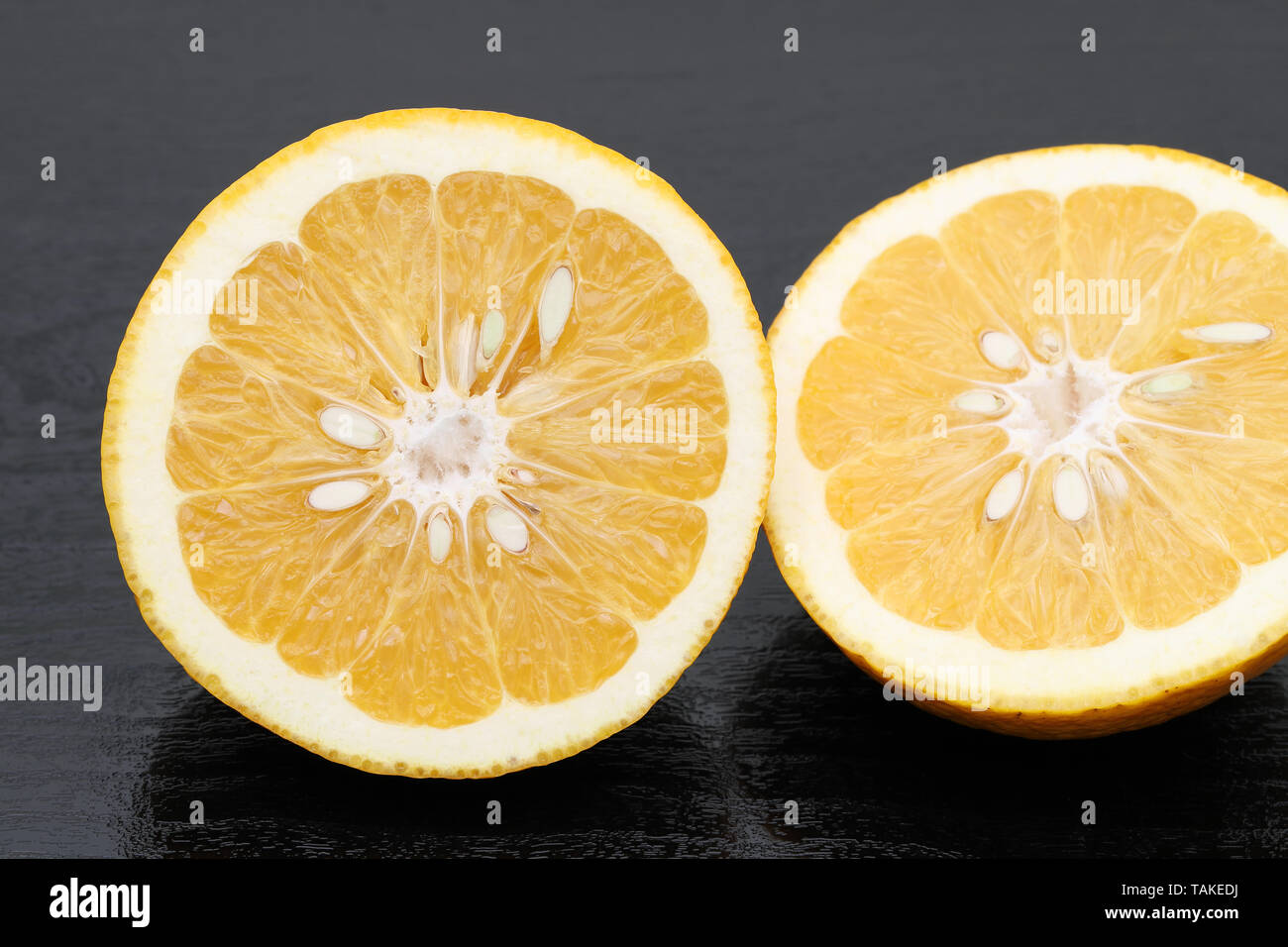 Die Hälfte der japanischen orange Zitrusfrüchten auf schwarzem Hintergrund Reif Stockfoto