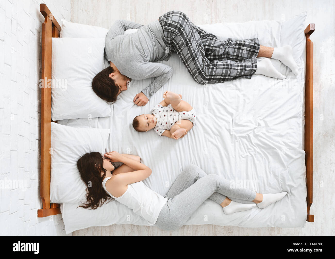 Lustige Familie mit einem neugeborenen Kind in der Mitte des Betts Stockfoto
