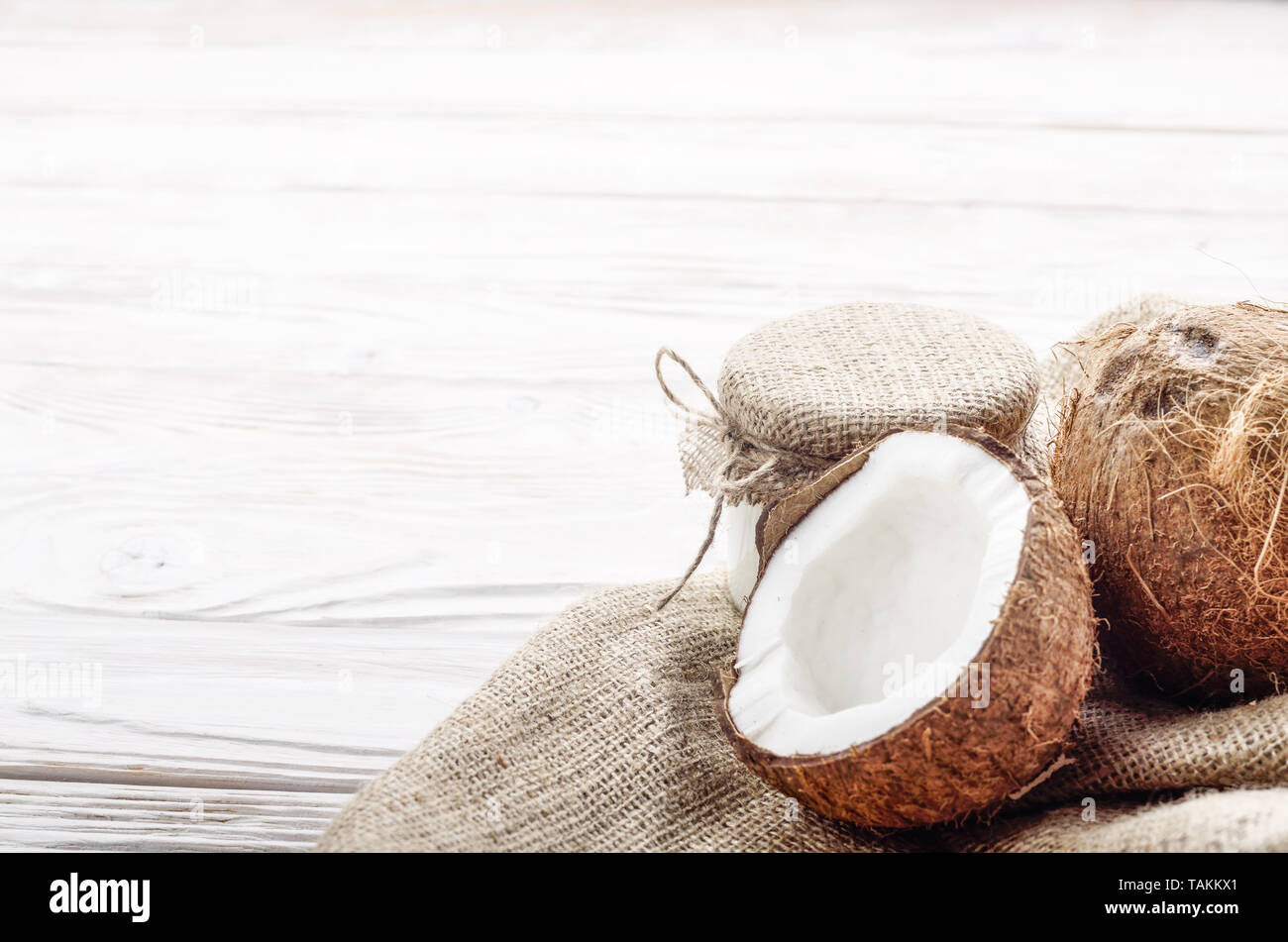 Coconut Shell mit Fleisch auf Hanf Sack auf weißen Küche aus Holz Tisch Stockfoto