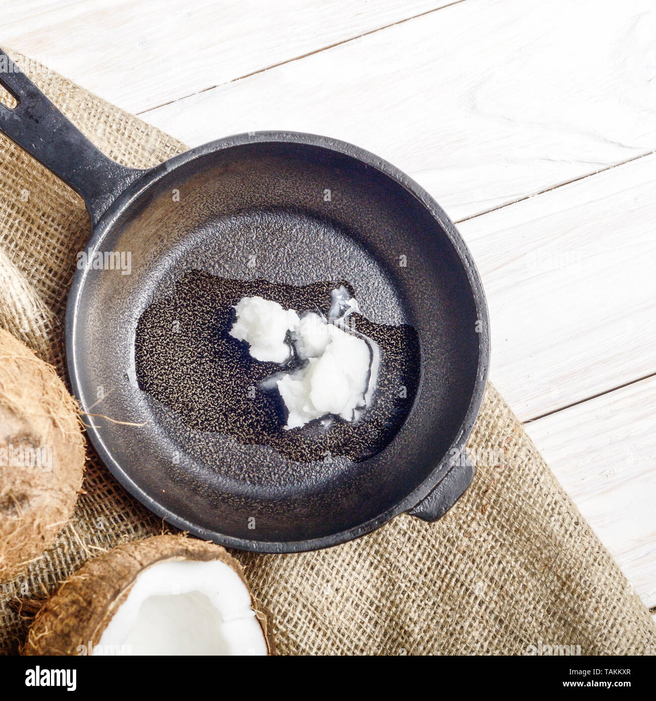 Kokosnuss, Shell mit Fleisch, Gusseisen Skillet auf Hanf Sack auf weißen Küche aus Holz Tisch Stockfoto