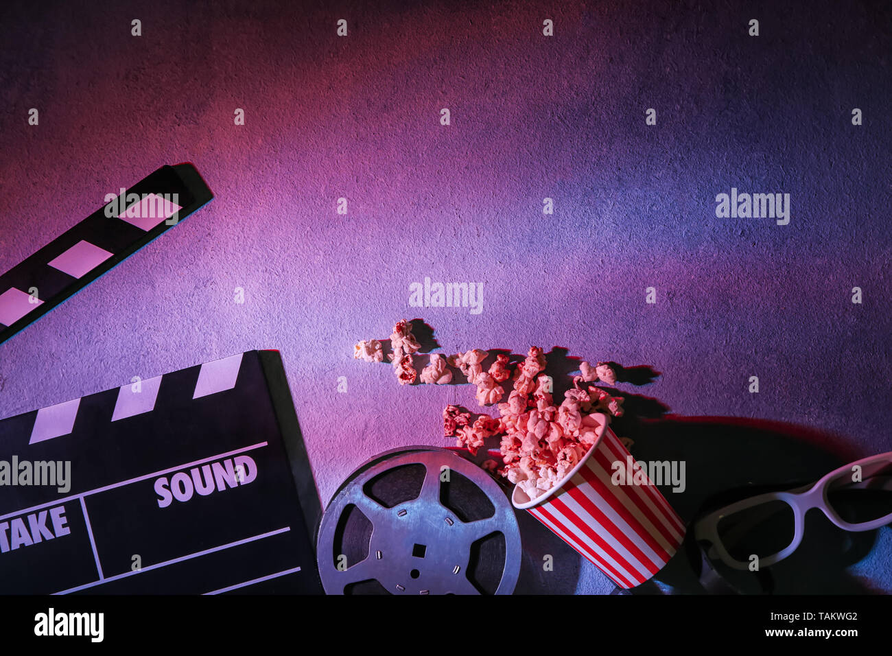 Filmklappe, Filmrolle mit Popcorn und Brille auf grauem Hintergrund Stockfoto