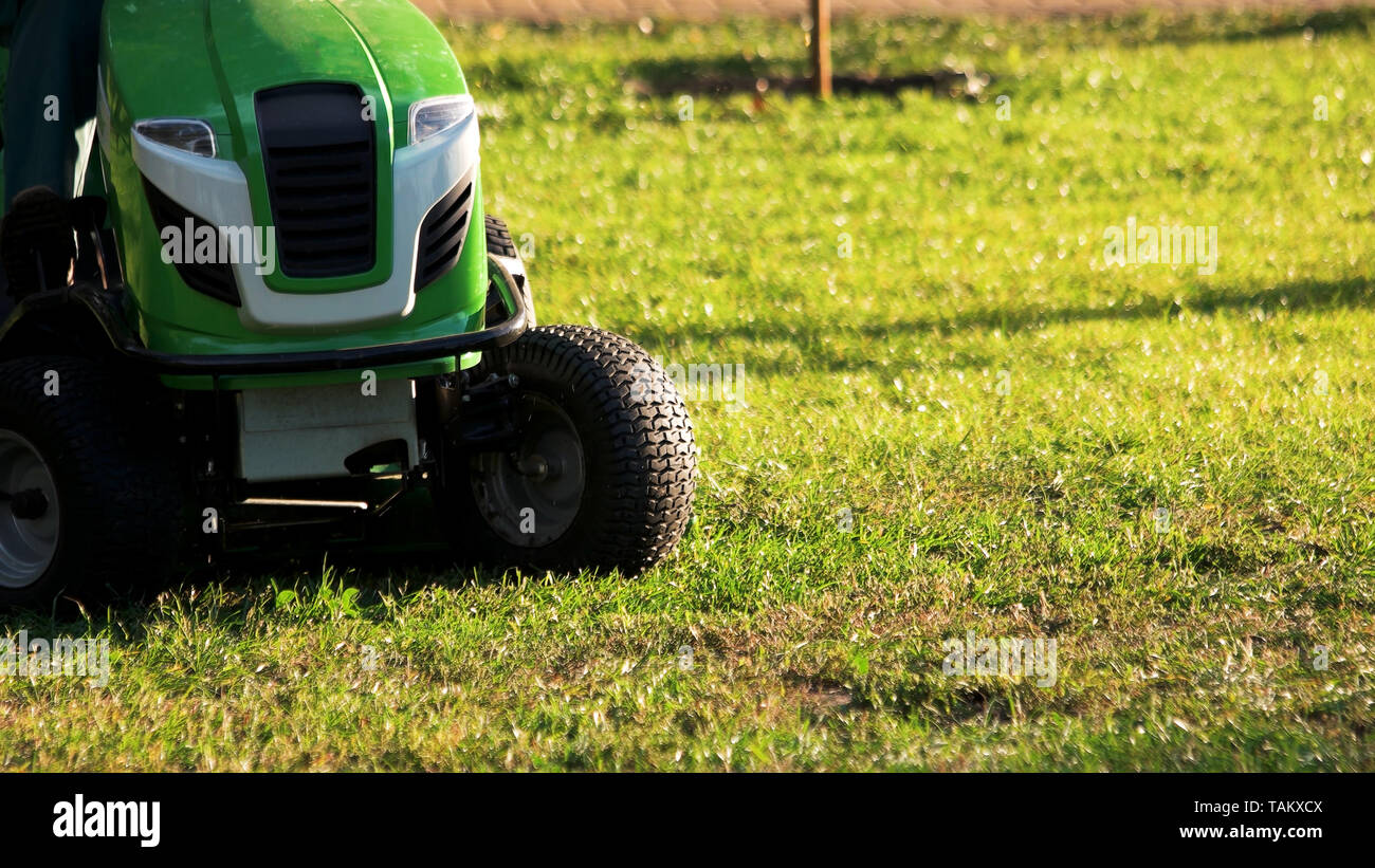 Grüne Rasenmäher Traktor. Rasenmäher Traktor im Freien an einem sonnigen Tag, Beschnittenes Bild. Stockfoto