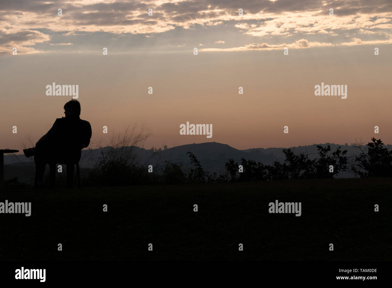 Eine Nahaufnahme des frühen Morgens Sonne, mit der Silhouette von jemand heraus ins Tal suchen. Stockfoto