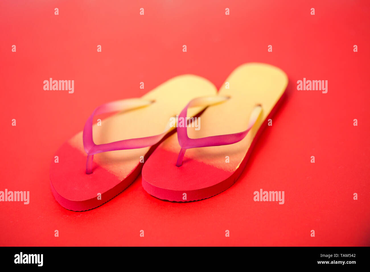 Paar bunte Flip Flops auf Korallen Hintergrund. Sommer Gelb Sommer Hausschuhe auf weißem Hintergrund. Flip flops