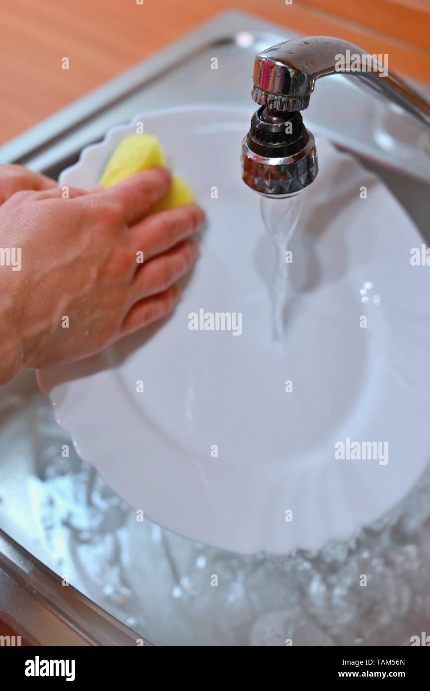 Hand abwaschen. Hand mit Schwamm und Waschbecken in der Küche Waschen schmutzige Geschirr - Teller. Stockfoto