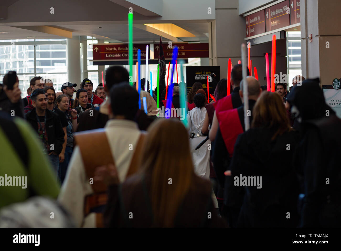 Star-Wars-Fans in Cosplay heben farbenfrohe Lichtschwerter auf der Star Wars Celebration 2019, McCormick Place, Chicago, Illinois, USA. Stockfoto