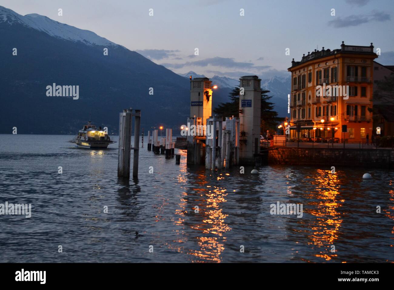 Varenna/Italien - April 6, 2014: schönen Panoramablick auf den Comer See mit einem Fahrgastschiff die Varenna Hafen bei Sonnenuntergang im Frühjahr. Stockfoto