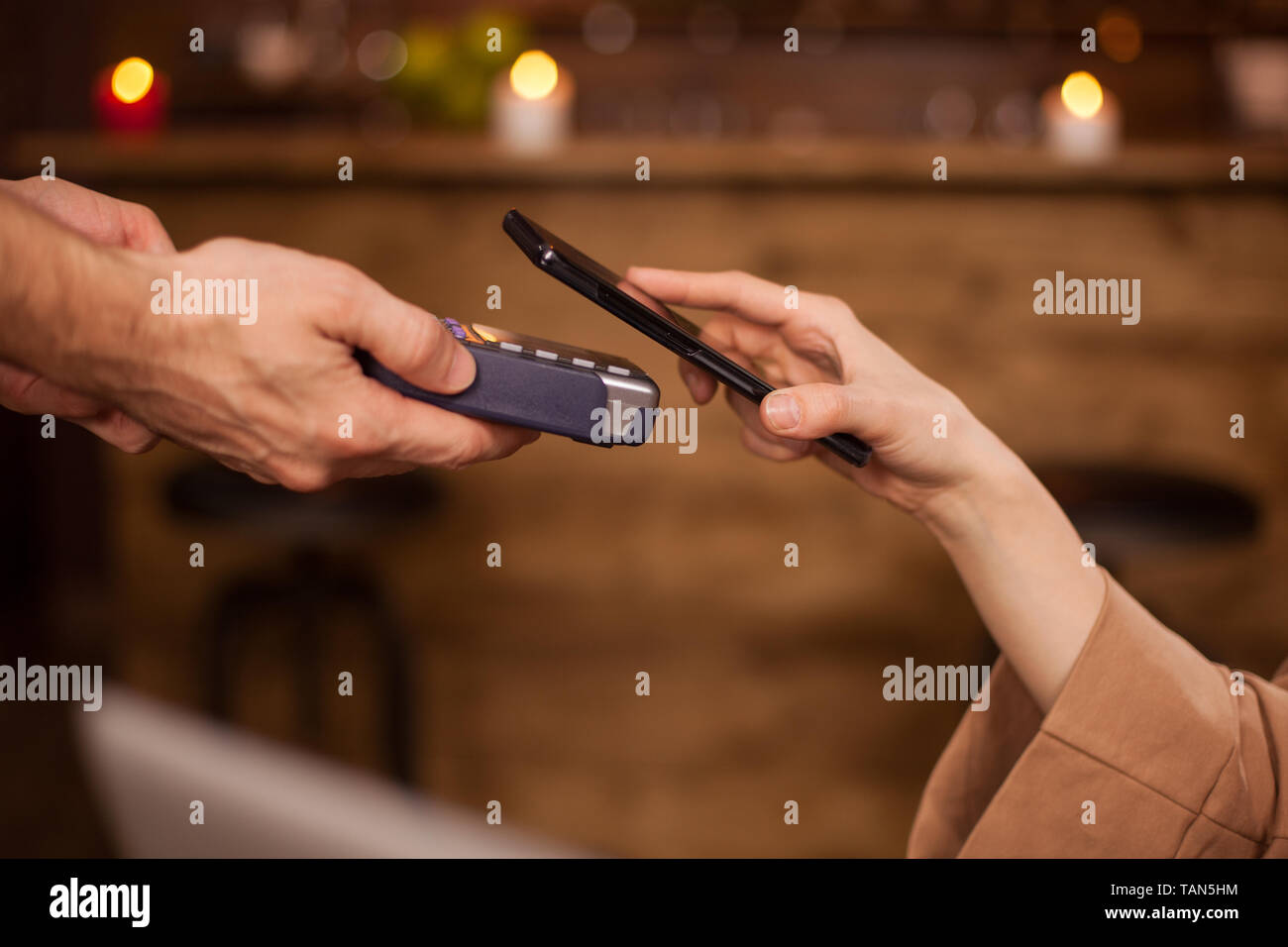 7/8 Bild der Frau Bezahlen mit Handy Technologie in einem Coffee Shop. Frau mit Handy. Kunden barista zu bezahlen. Stockfoto