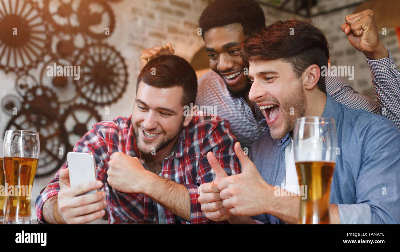 Fußball-Fans, Fußball auf dem Smartphone im Pub Stockfoto