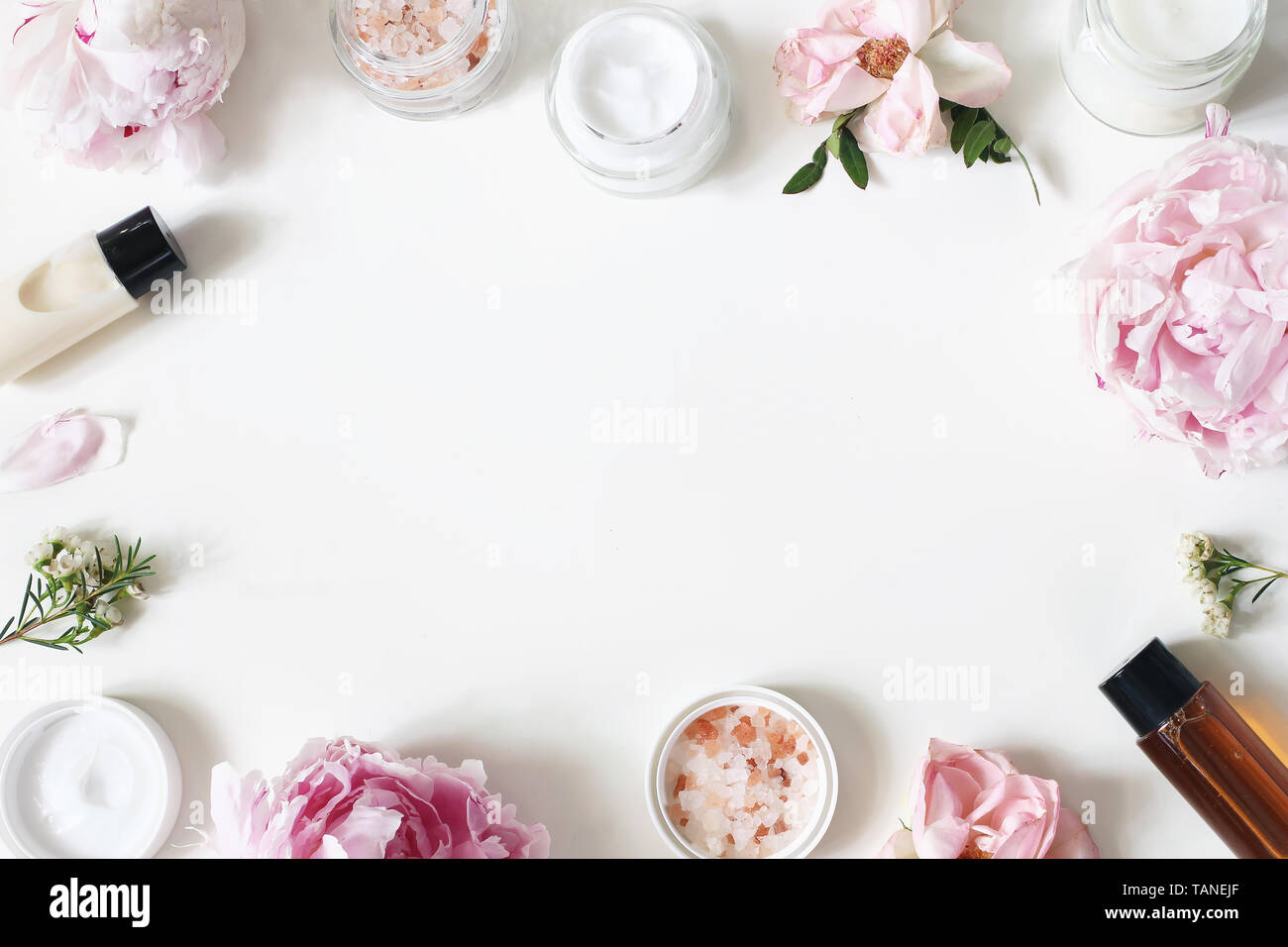 Styled Schönheit frame, Web Banner. Hautcreme, Shampoo, tonicum Flaschen, Blätter, Rose, Pfingstrose Blumen und Salz auf hite Tabelle Hintergrund. Organische Stockfoto