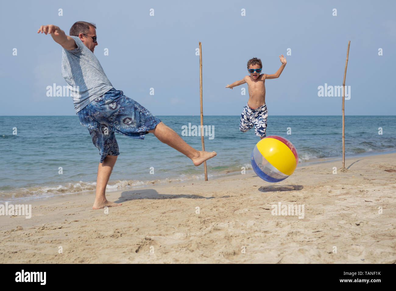 Vater und Sohn spielen Fußball auf dem Strand im Sommer Tag Zeit. Menschen, die Spaß im Freien. Konzept der freundliche Familie. Stockfoto
