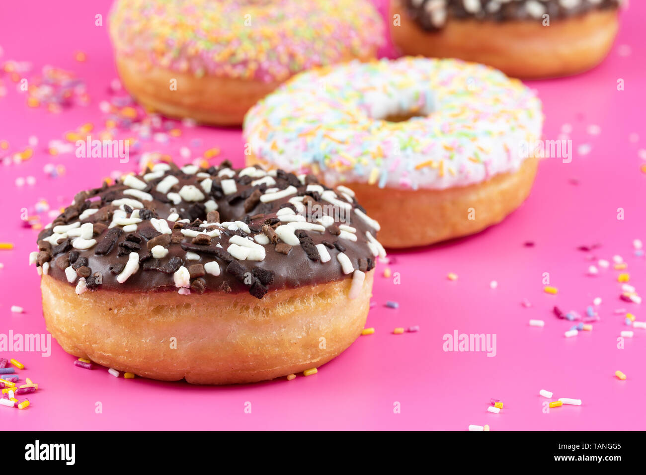 Iced Donuts mit gegen eine lebendige rosa Hintergrund fotografiert Streuseln. Stockfoto