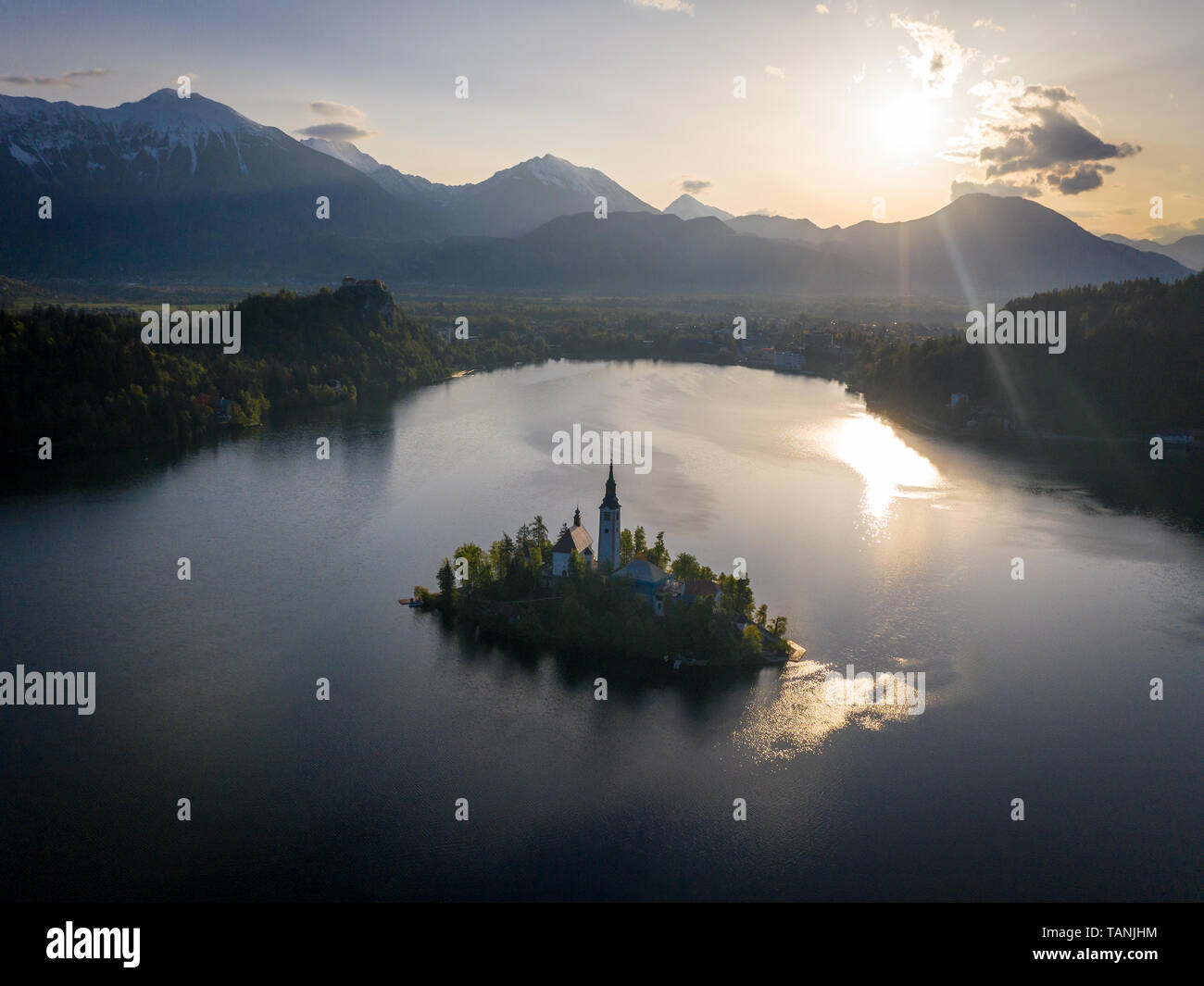 Der See von Bled Kirche Luftaufnahme kurz nach Sonnenaufgang. Turm der St. Marys Kirche Mariä Himmelfahrt Kirche im Schatten. Es gibt die Julischen Alpen in backgrou Stockfoto