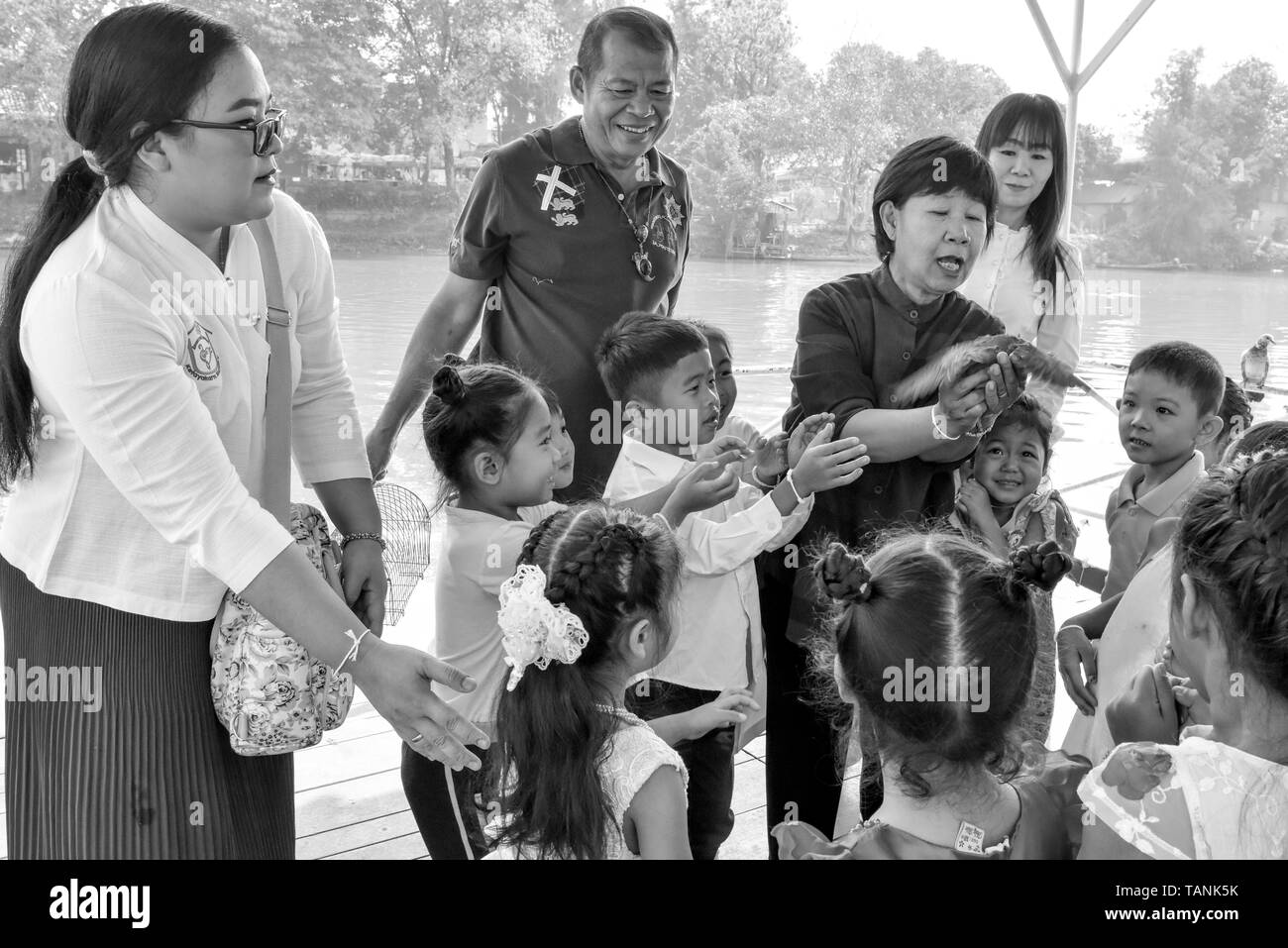 Thai Kinder und ihre Erzieher release Vögel neben Fluss Ping Chiang Mai. In der buddhistischen Religion, einige Leute glauben, dass eine Freigabe der Tiere wieder in der Natur Hilfe kann eine individuelle Verdienst erwachsen. Stockfoto