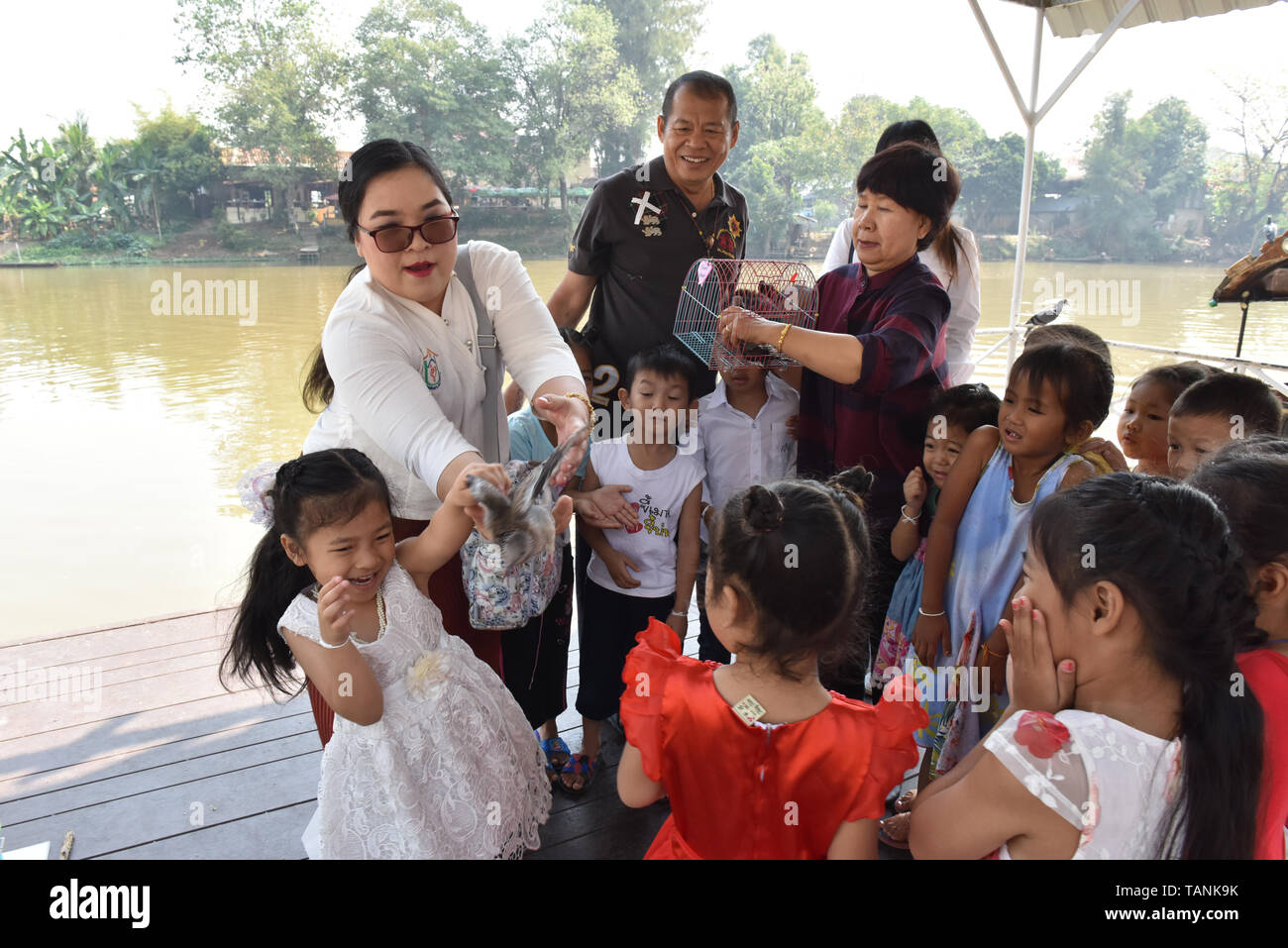 Thai Kinder und ihre Erzieher release Vögel neben Fluss Ping Chiang Mai. In der buddhistischen Religion, einige Leute glauben, dass eine Freigabe der Tiere wieder in der Natur Hilfe kann eine individuelle Verdienst erwachsen. Stockfoto