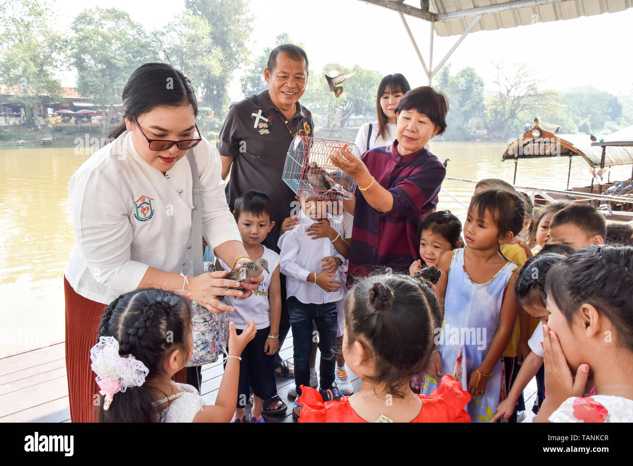 Thai Kinder und ihre Erzieher release Vögel neben Fluss Ping Chiang Mai. In der buddhistischen Religion, einige Leute glauben, dass eine Freigabe der Tiere wieder in der Natur Hilfe kann eine individuelle Verdienst erwachsen. Stockfoto