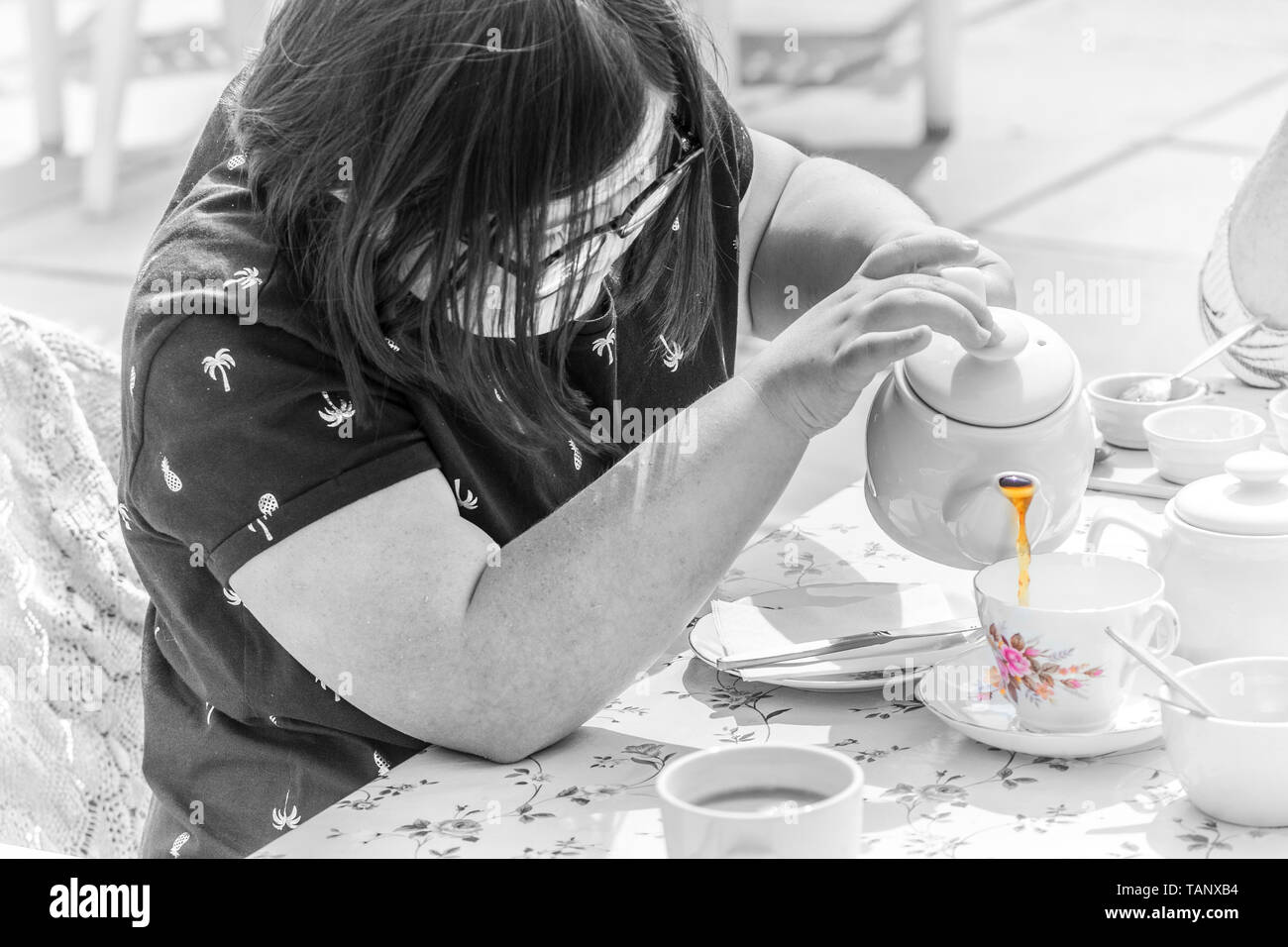 Mädchen mit Down-syndrom Leben genießen und gießen Sie eine Tasse Tee. Stockfoto