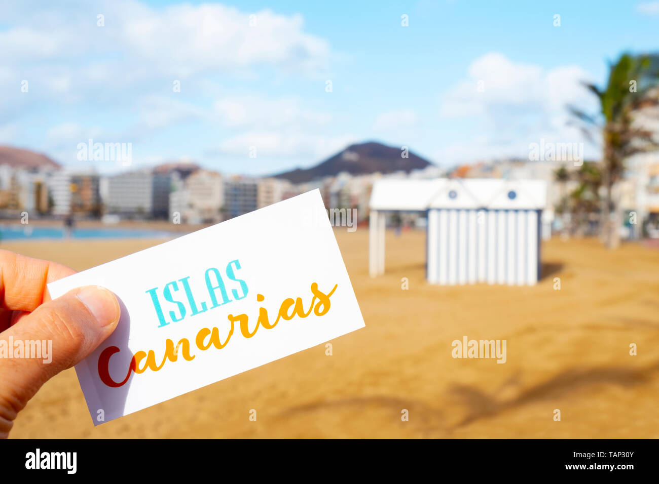 Nahaufnahme der Hand eines kaukasischen Mann hält ein Schild mit dem Text Islas Canarias Kanarische Inseln auf Spanisch geschrieben, bei Playa del Ingles, in Ma Stockfoto