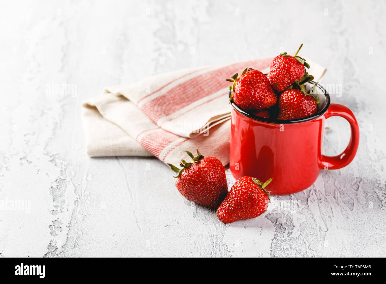 Frische Erdbeeren in rot Emaille Tasse auf grauem Hintergrund. Platz für Text. Stockfoto
