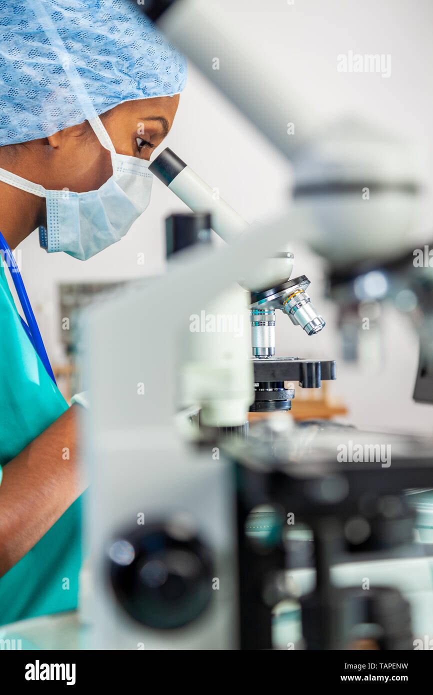 Asiatische Frau Arzt oder Wissenschaftler mit Ihrem Mikroskop in einem medizinischen Labor oder Labor. Stockfoto