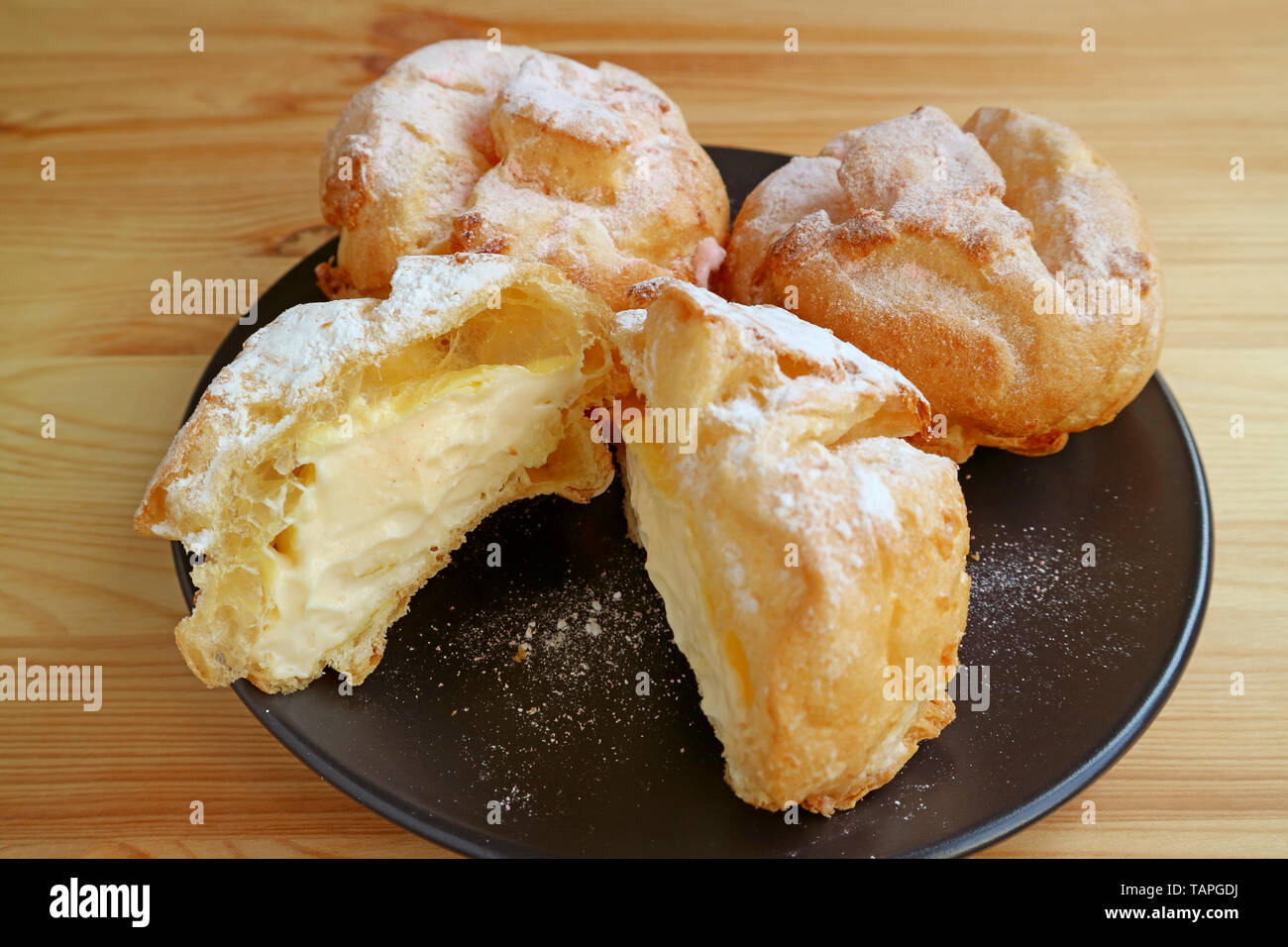 Platte der Französischen Windbeutel gefüllt mit Vanillesauce Creme oder Choux a la Creme Gebäck serviert auf hölzernen Tisch Stockfoto