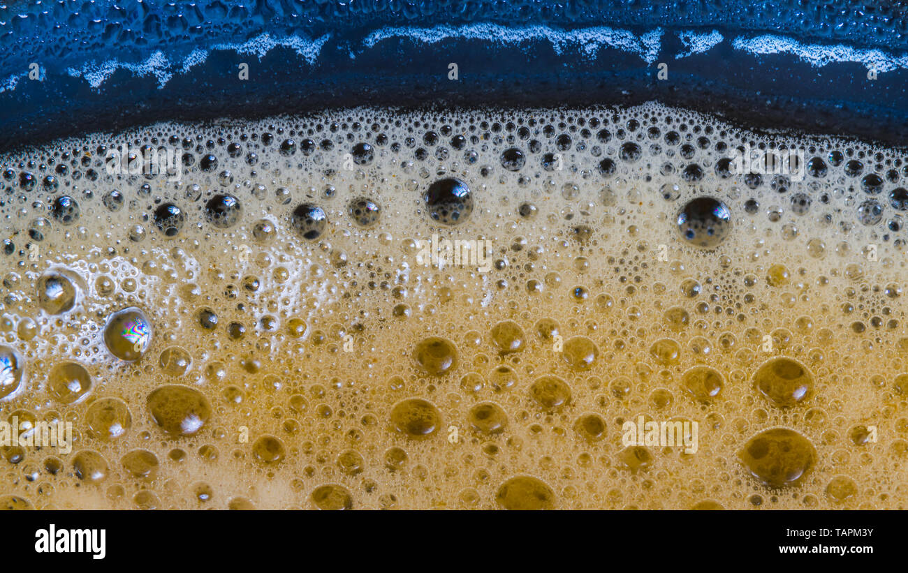 Schaum Oberflächenstruktur. Blase trinken Detail. Aromatische Kaffee Tasse. Erfrischende Koffein trinken in blauem Glas. Wasser tropfen. Abstrakte schaumigen Hintergrund. Stockfoto