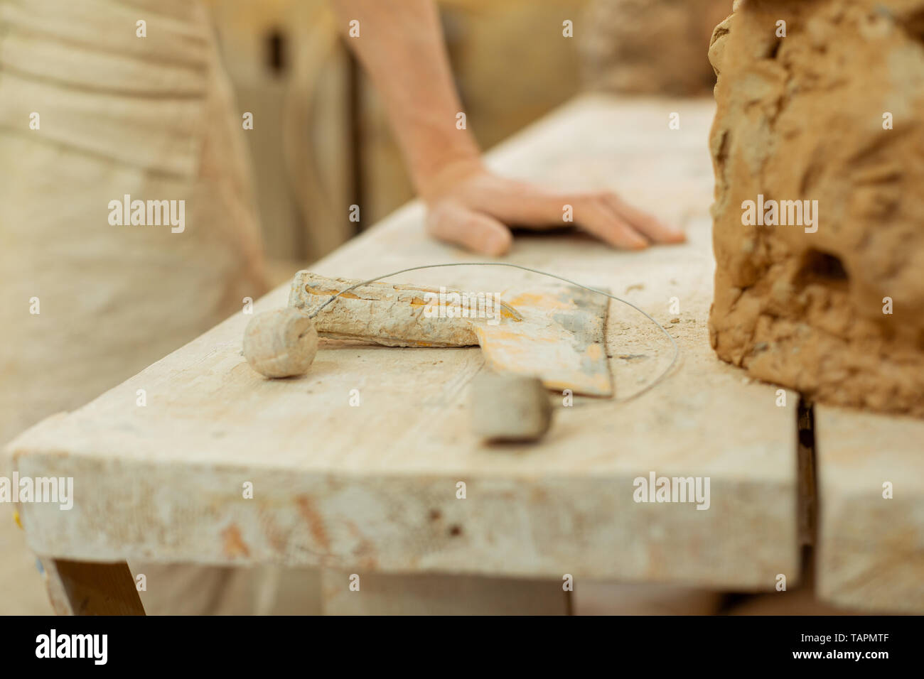 Intensiven Arbeitstag. Mann lehnte sich auf einem Arbeitstisch in Ton Schmutz bedeckt und Denken auf benötigten Werkzeuge Stockfoto